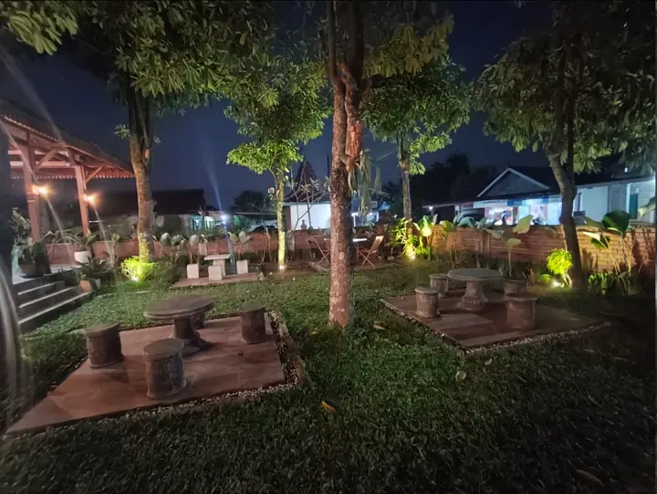 Sudut taman teduh dengan meja dan kursi batu untuk latar natural.